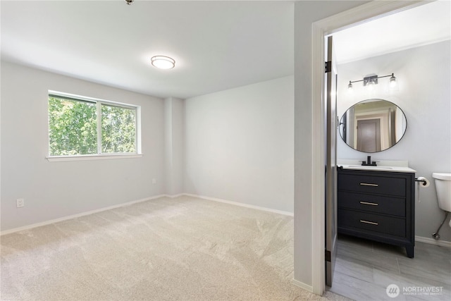 bedroom featuring light colored carpet, baseboards, and a sink