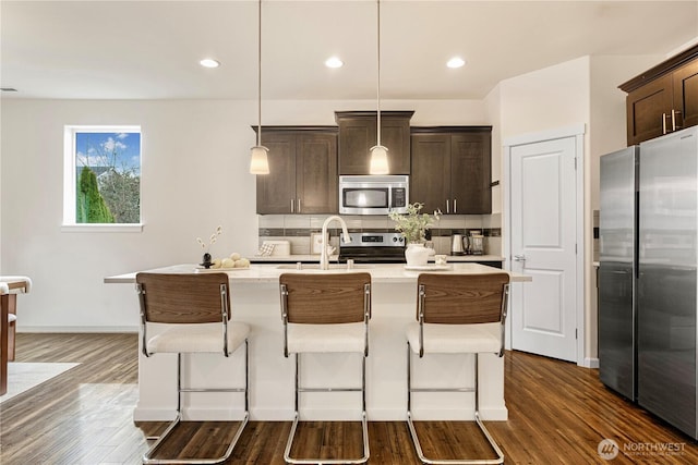 kitchen with tasteful backsplash, dark brown cabinetry, stainless steel appliances, and dark wood-style flooring