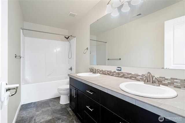 bathroom featuring a sink, backsplash, and toilet