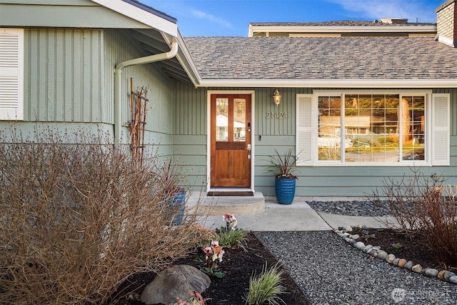 view of exterior entry with a shingled roof