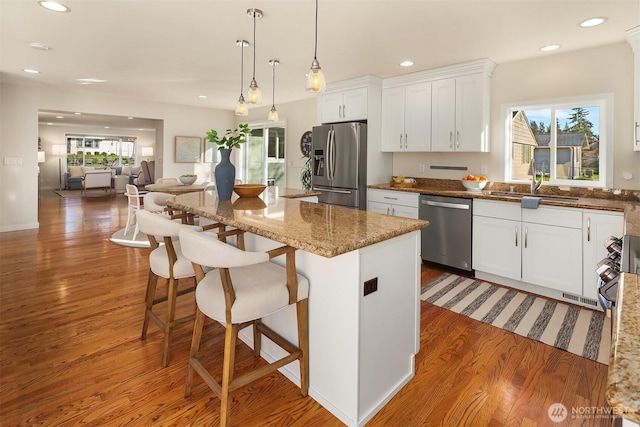 kitchen featuring a wealth of natural light, appliances with stainless steel finishes, white cabinetry, and wood finished floors