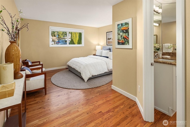 bedroom featuring baseboards, light wood-style floors, and a sink