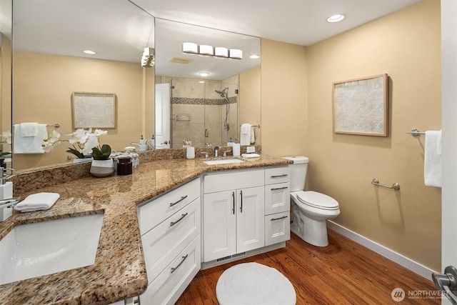 full bathroom with wood finished floors, a stall shower, toilet, and a sink