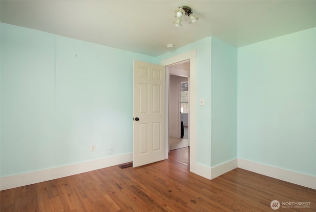 empty room featuring visible vents, baseboards, and wood finished floors