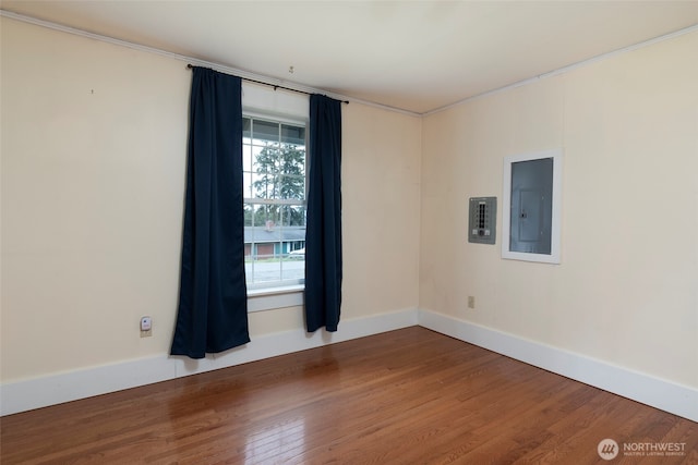 unfurnished room featuring electric panel, wood finished floors, and baseboards