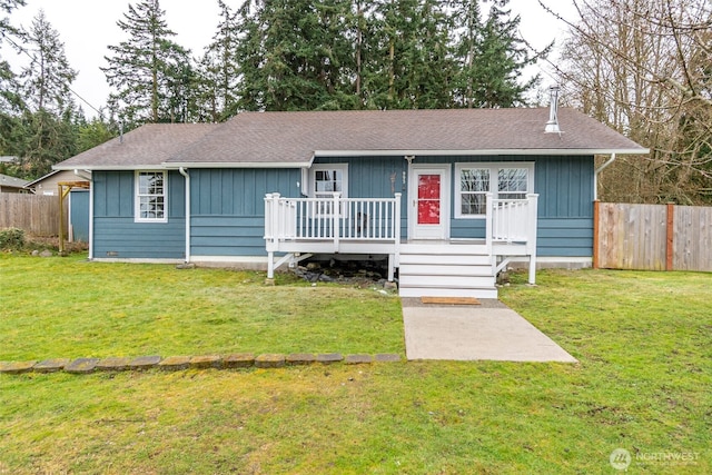 single story home with roof with shingles, board and batten siding, a front yard, and fence