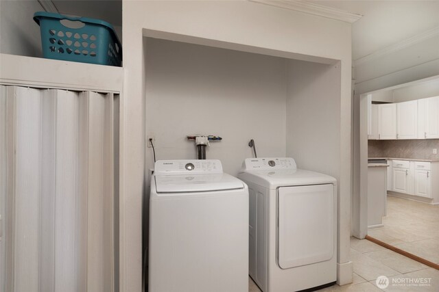 laundry room featuring light tile patterned floors, washing machine and dryer, laundry area, and crown molding