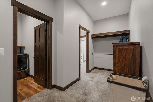corridor with washer / dryer, light colored carpet, and baseboards