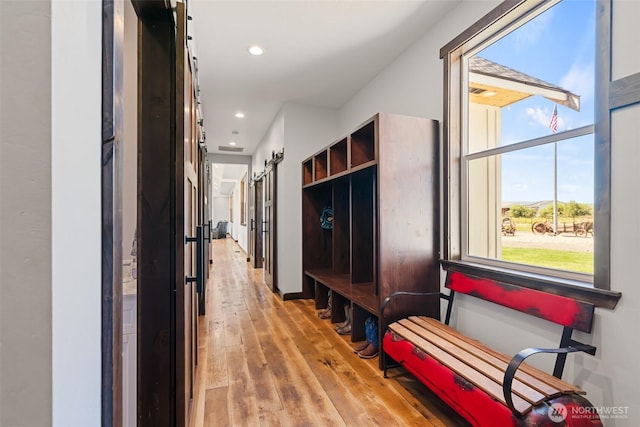 mudroom featuring light wood-style flooring, recessed lighting, and a barn door