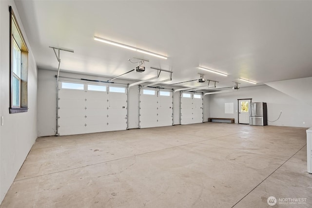 garage with freestanding refrigerator and a garage door opener