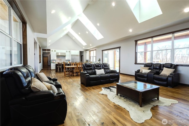 living area with baseboards, recessed lighting, a skylight, high vaulted ceiling, and hardwood / wood-style flooring