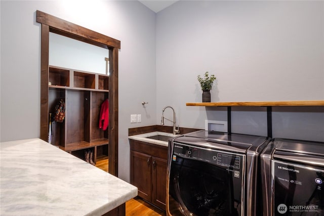 washroom featuring cabinet space, light wood finished floors, washer and dryer, and a sink