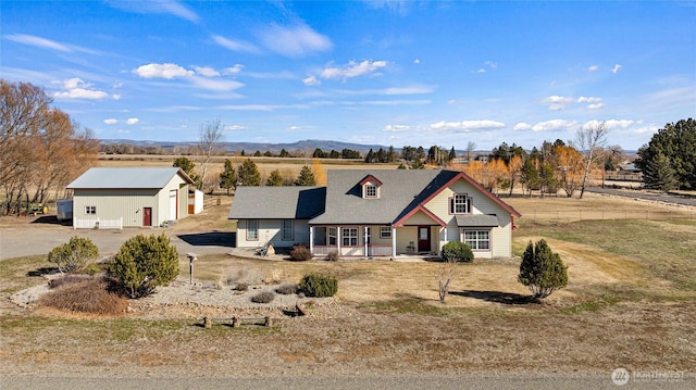 view of front facade featuring a garage, a mountain view, an outbuilding, and dirt driveway