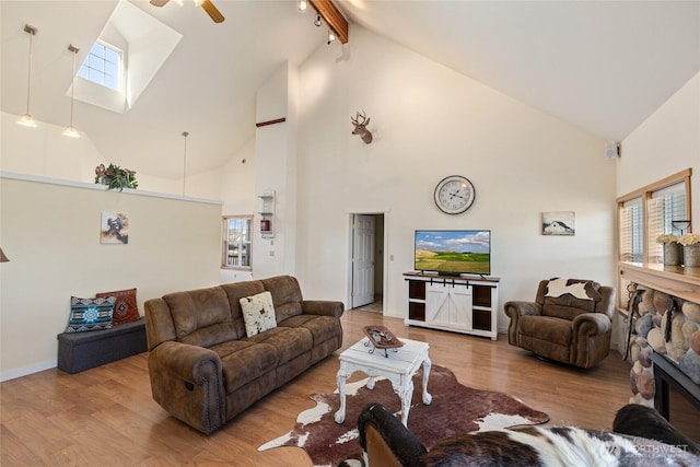 living room with wood finished floors, baseboards, a skylight, a fireplace, and beamed ceiling