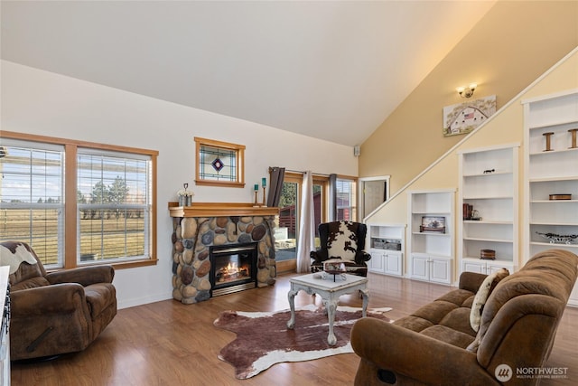 living room featuring wood finished floors, a fireplace, baseboards, and high vaulted ceiling