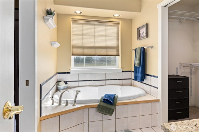 bathroom with a walk in closet and a bath