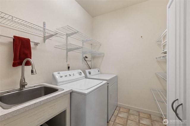 washroom with a sink, baseboards, laundry area, and washer and clothes dryer