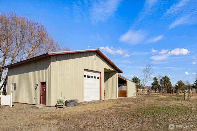 detached garage with dirt driveway and fence