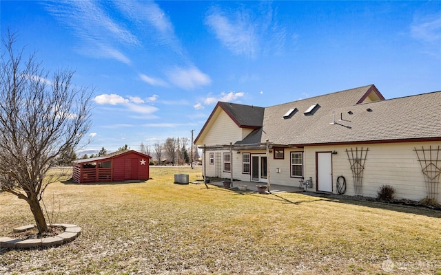 rear view of property featuring central AC, a yard, and roof with shingles