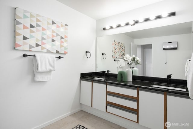 bathroom with a sink, baseboards, double vanity, and tile patterned flooring