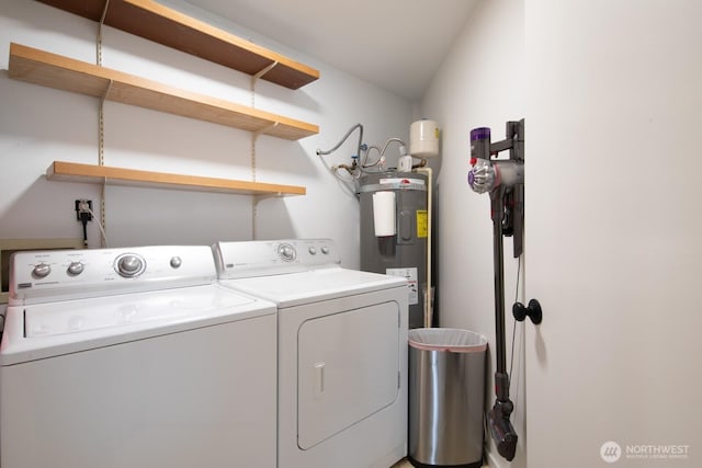 clothes washing area with washing machine and dryer, water heater, and laundry area