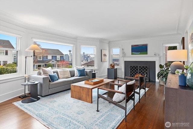 living room with baseboards, a lit fireplace, and dark wood-style floors