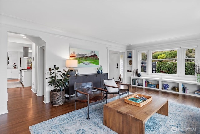 living area with arched walkways and wood finished floors