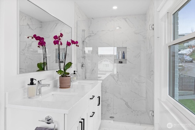 full bathroom featuring a sink, a marble finish shower, recessed lighting, and double vanity