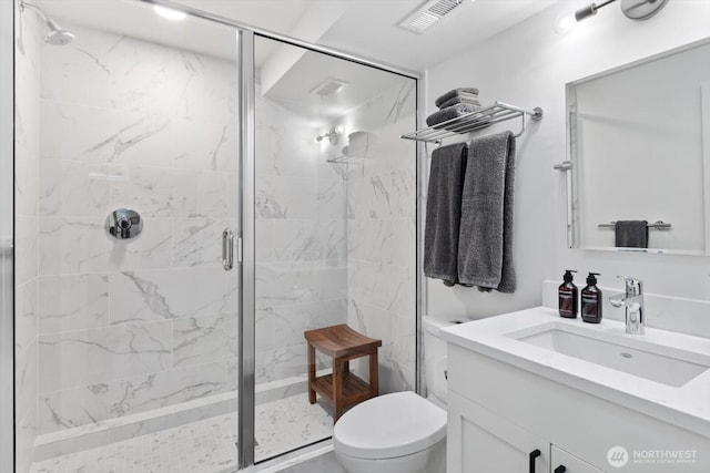 full bath with a marble finish shower, visible vents, toilet, and vanity