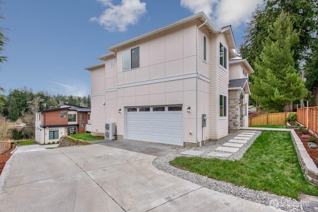 back of house featuring concrete driveway, an attached garage, fence, and stone siding