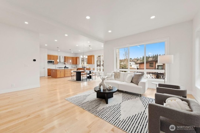 living area featuring a notable chandelier, recessed lighting, baseboards, and light wood finished floors