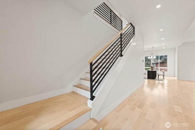 stairway with a notable chandelier, recessed lighting, baseboards, and wood finished floors