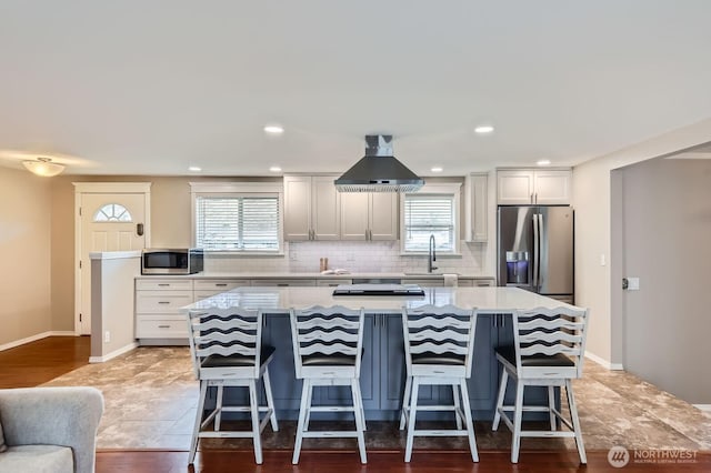 kitchen with stainless steel appliances, plenty of natural light, range hood, and a center island