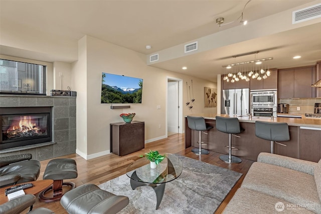 living area featuring visible vents, light wood-type flooring, and baseboards