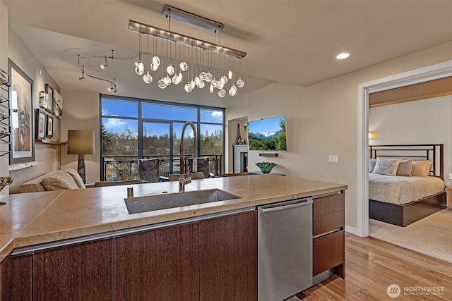 kitchen with a sink, light wood-style floors, dishwasher, decorative light fixtures, and open floor plan