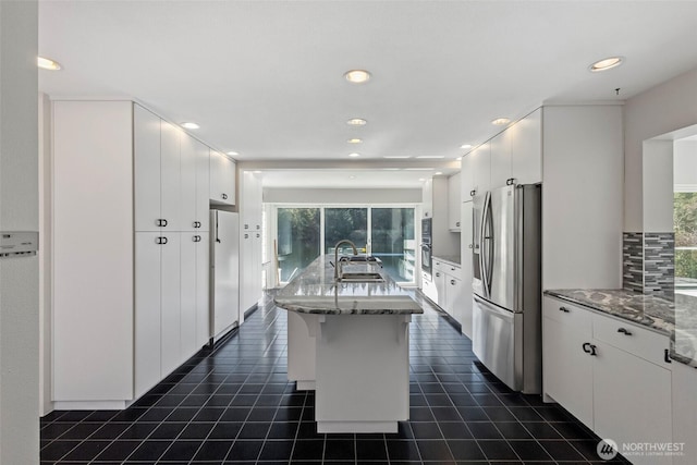 kitchen featuring white cabinets, stone countertops, appliances with stainless steel finishes, and a sink