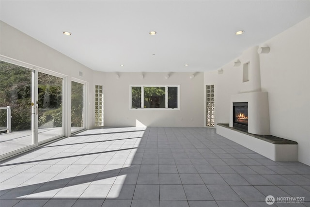 unfurnished living room featuring recessed lighting, a glass covered fireplace, and tile patterned flooring