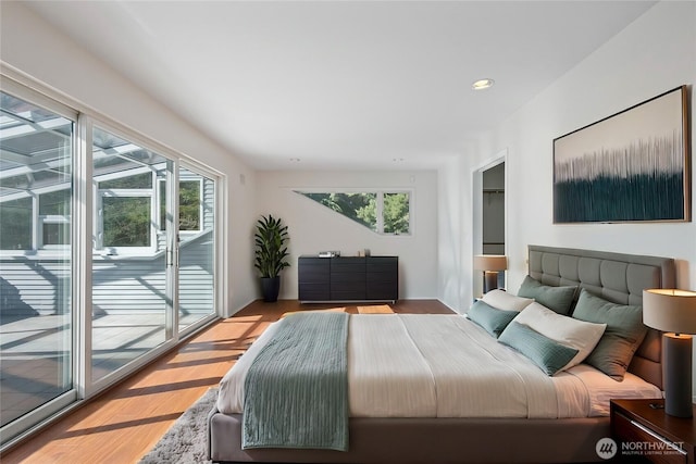 bedroom with recessed lighting, multiple windows, wood finished floors, and access to outside