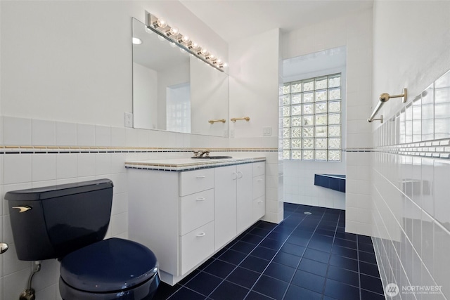 full bath with toilet, tile walls, vanity, and tile patterned flooring