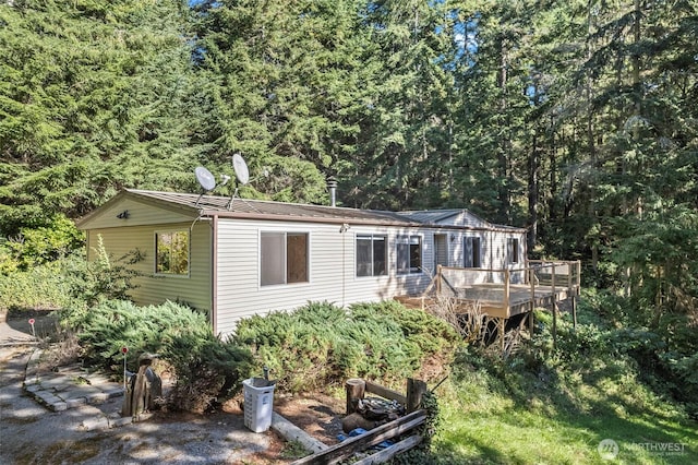 view of front facade featuring a wooded view and a wooden deck