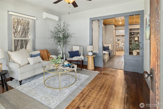 living room featuring crown molding, ceiling fan, decorative columns, a wall mounted AC, and wood-type flooring