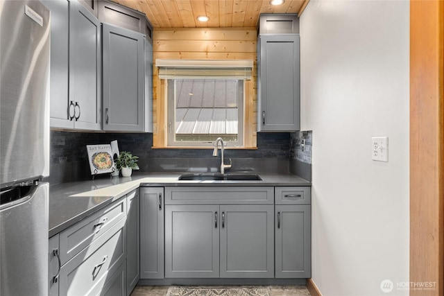 kitchen with gray cabinets, freestanding refrigerator, and a sink