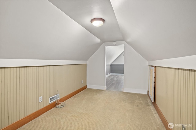 additional living space with baseboards, visible vents, lofted ceiling, and carpet floors