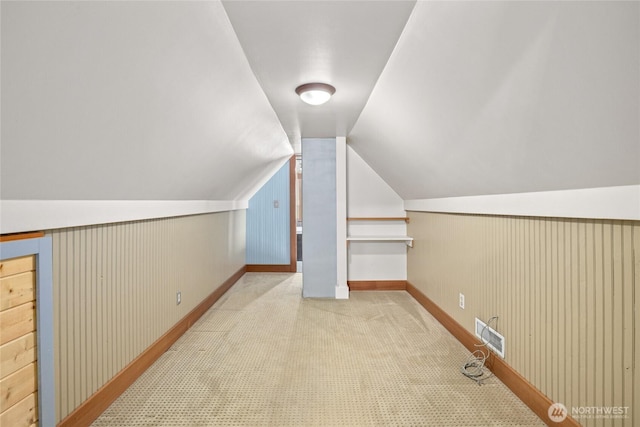 additional living space featuring visible vents, carpet floors, wood walls, and vaulted ceiling