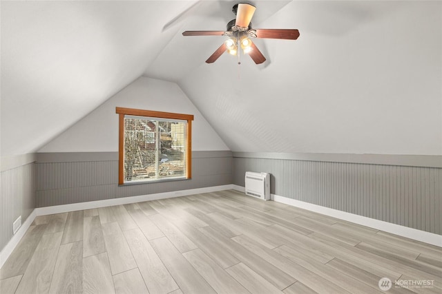 bonus room featuring a wainscoted wall, a ceiling fan, light wood-type flooring, and lofted ceiling