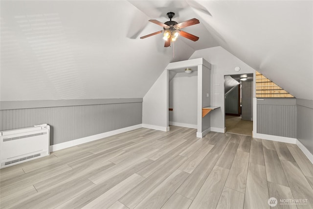 bonus room with vaulted ceiling, heating unit, wood finished floors, and ceiling fan
