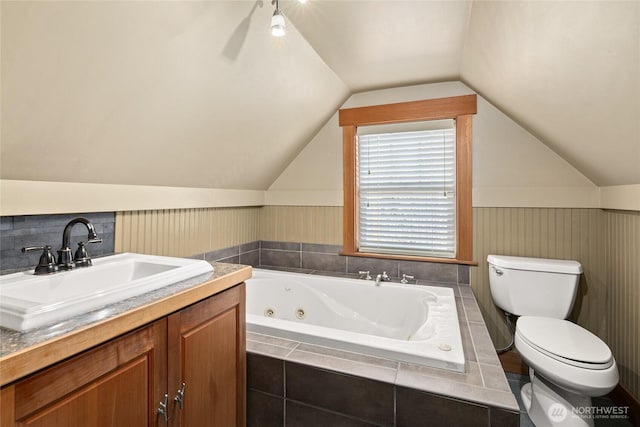 full bathroom featuring a wainscoted wall, toilet, a whirlpool tub, vanity, and vaulted ceiling