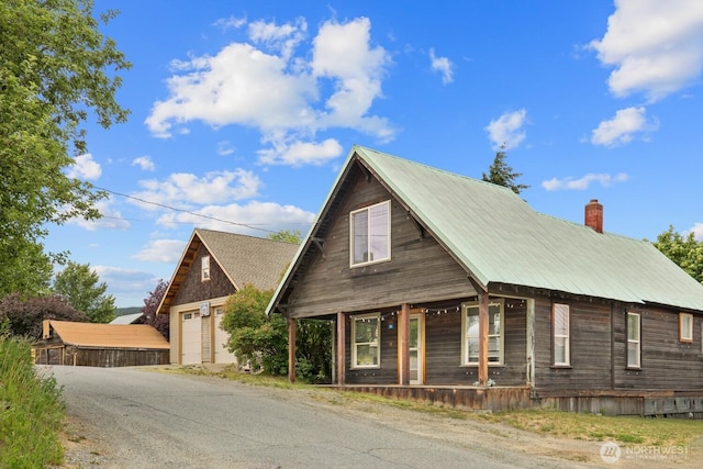 313 S 2nd St, Roslyn, WA 98941 - view of front of property with a porch, a garage, a metal roof, an outbuilding, and a chimney
