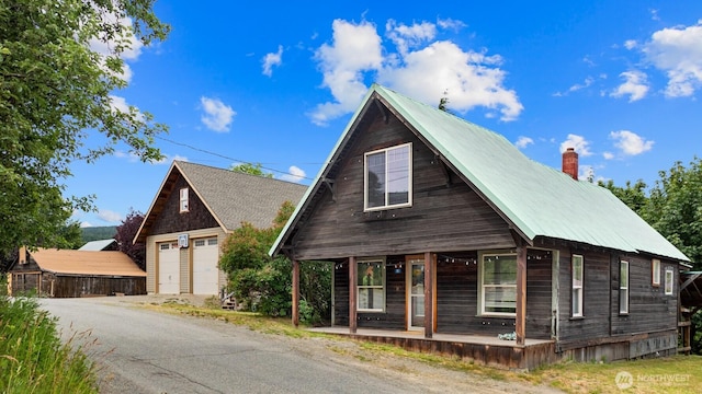 313 S 2nd St, Roslyn, WA 98941 - view of front facade with a porch, a detached garage, a chimney, an outbuilding, and a metal roof