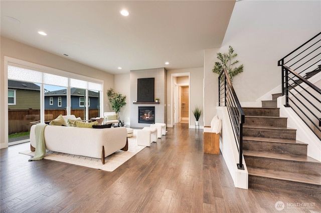 living area with baseboards, dark wood finished floors, recessed lighting, stairs, and a large fireplace